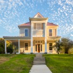 Exterior photo of the front of a 2-story house with yellow siding and a red roof. thumb