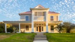 Exterior photo of the front of a 2-story house with yellow siding and a red roof. thumb